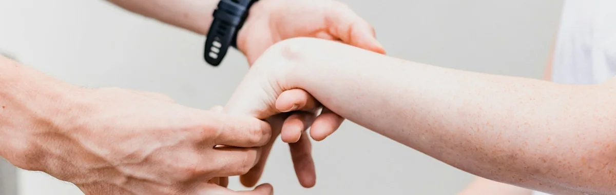 Handen die de arm van een patiënt door een beweging begeleiden